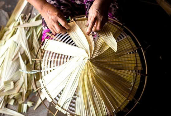 Cận cảnh bàn tay một người thợ đang hoàn thiện công đoạn làm một chiếc nón lá truyền thống. Ảnh: NVCC.