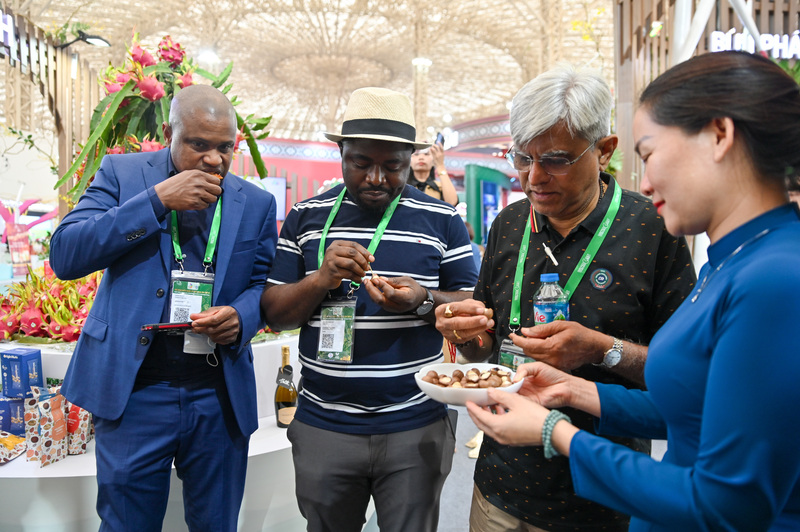 Các doanh nghiệp quốc tế thưởng thức hạt mác ca tại gian hàng của tỉnh Lâm Đồng.