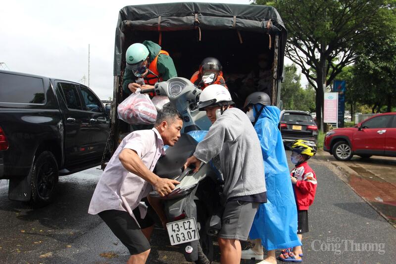 Ông Nguyễn Dũng cùng người dân đưa xe máy lên xe tải nhỏ để hỗ trợ chở qua đoạn nước ngập sâu