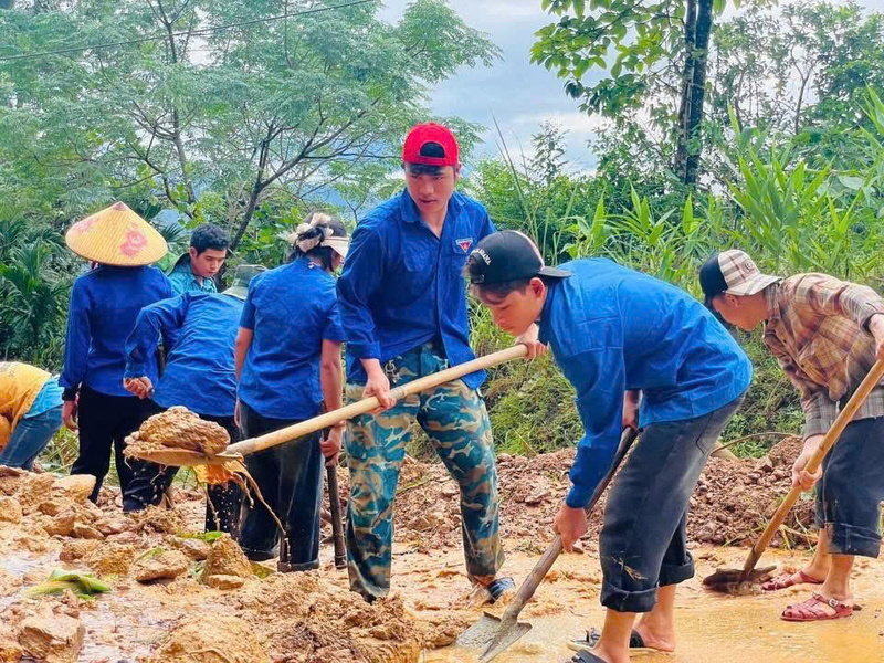 Đoàn viên thanh niên của xã cùng tham gia để san gạt bùn đất. Ảnh: Tuệ Lâm