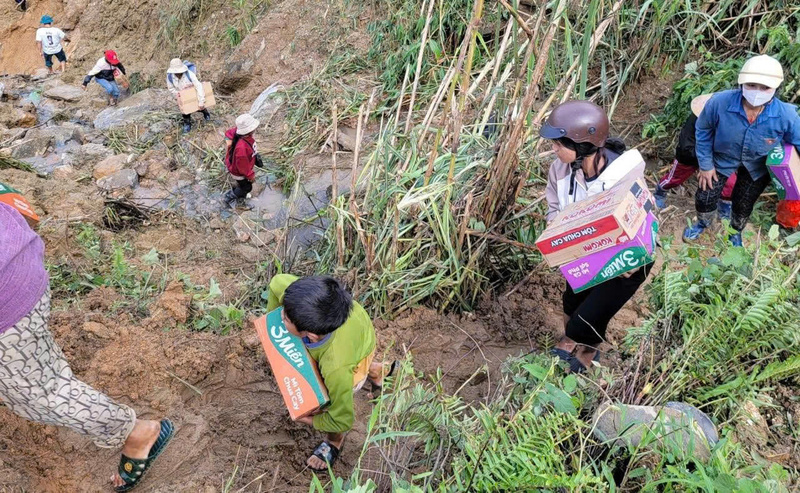 Hơn 100 người gồm công an, dân quân, cán bộ và thanh niên mở tuyến đường mòn băng qua điểm sạt lở để tiếp tế lương thực. Ảnh: Tuệ Lâm