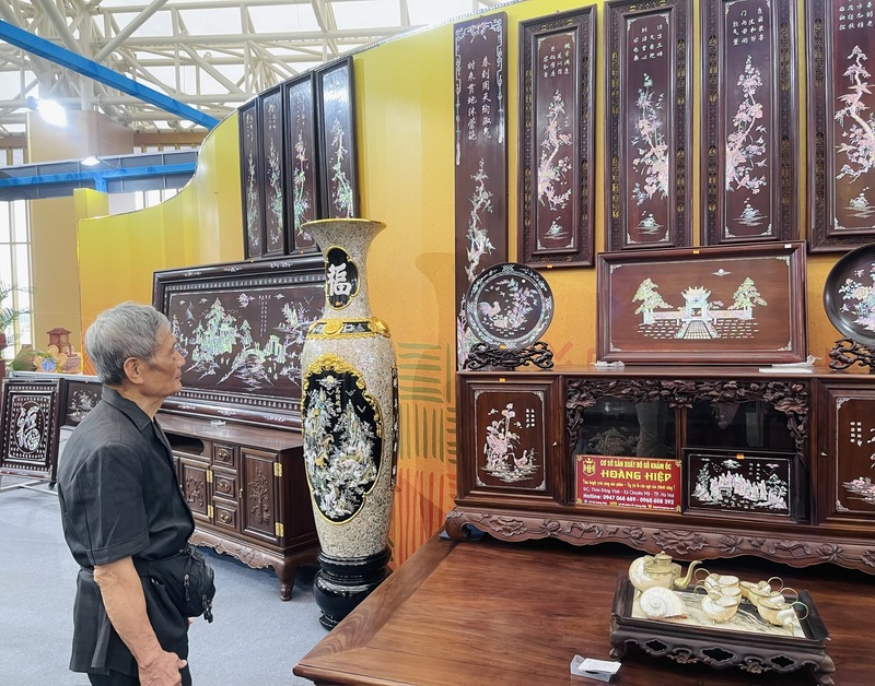 Khách hàng đang ngắm nhìn vẻ đẹp lấp lánh của những tác phẩm ốc xà cừ bộ tranh “Tứ quý – Trúc Cúc Mai Lan”. Ảnh: Nguyễn Hương