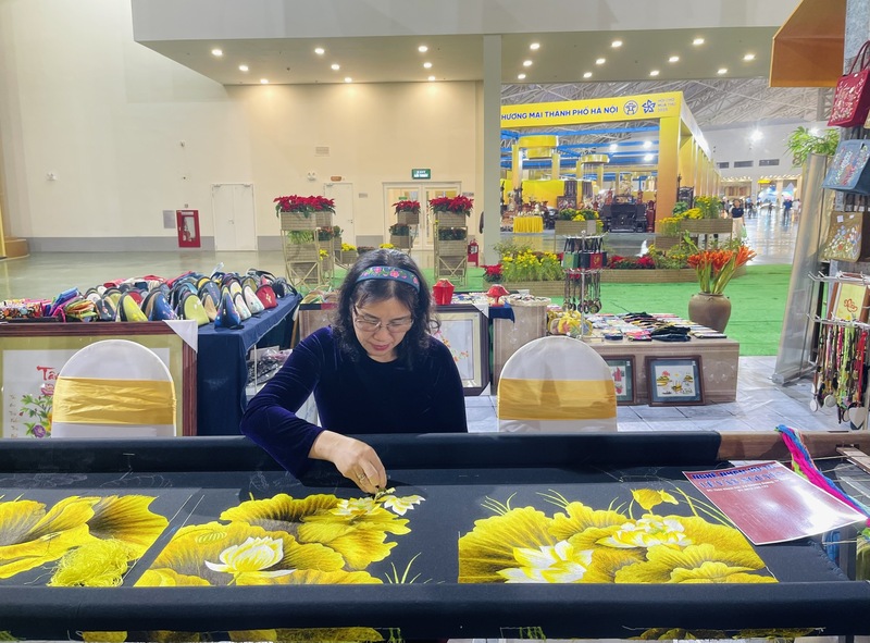 Nghệ nhân Lê Thị Xuân với bức tranh thêu dang dở ngay tại Hội chợ Mùa Thu lần thứ nhất - 2025. Ảnh: Nguyễn Hương