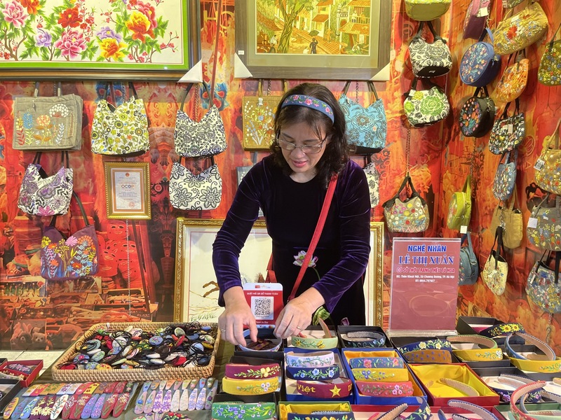 Nghệ nhân Lê Thị Xuân cẩn thận chăm chút cho sản phẩm của mình tại gian hàng. Ảnh: Nguyễn Hương