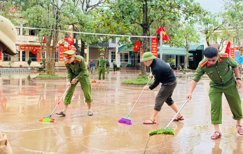 Lực lượng công an được huy động quét dọn bùn đất giúp các trường học.