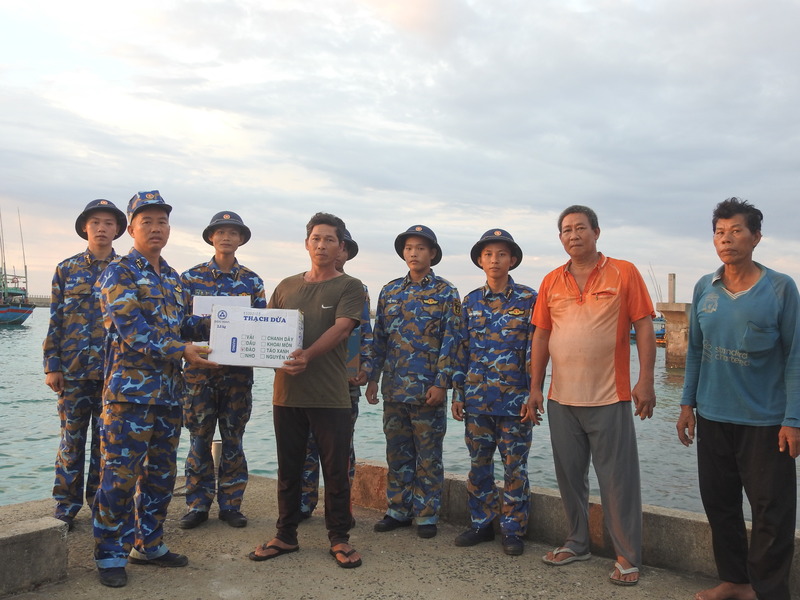 Trung tá Đặng Văn Tài - Chính trị viên đảo Đá Tây tặng quà cho ngư dân vào khu neo đậu tránh bão. Ảnh: Ngọc Ánh