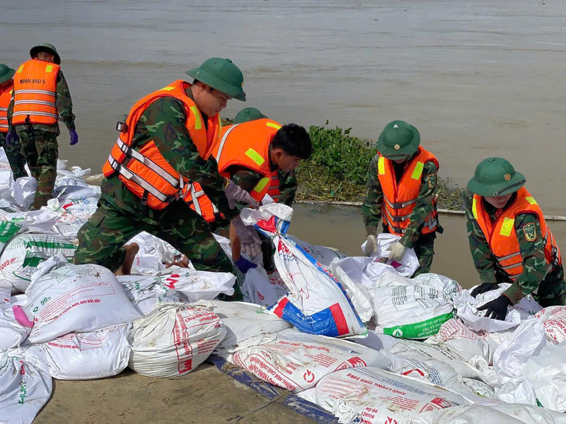 Hơn 1.000 người gồm lực lượng công an, bộ đội, dân quân và người dân địa phương được huy động suốt ngày đêm để gia cố tạm thời bằng bao cát, đá hộc và vận chuyển cát san nền chống sạt lở. Ảnh: Nguyễn Dương
