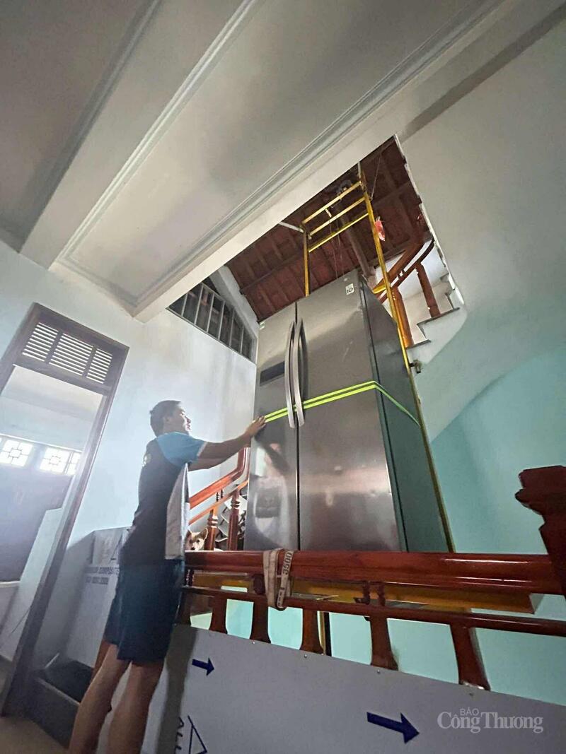 Anh Lê Thanh Nguyên Vũ đang dùng máy tời đưa tủ lạnh lên tầng 2 tránh lũ.