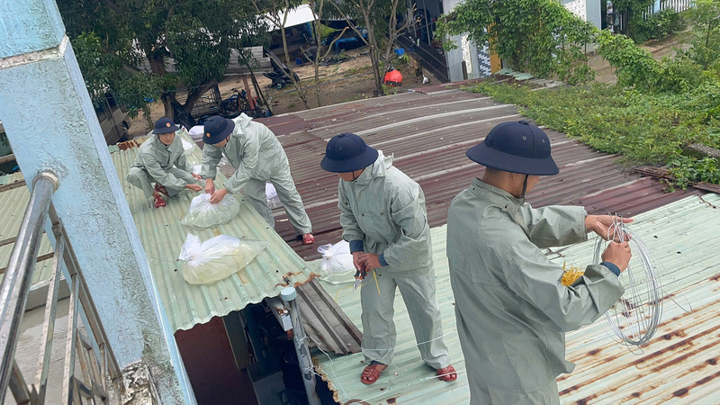 Hỗ trợ người dân gia cố mái nhà. Ảnh: Bình An