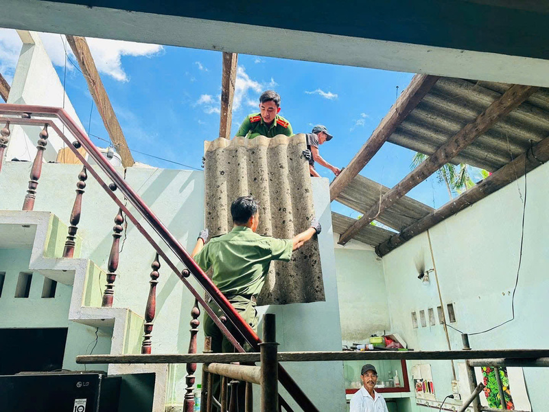 Cán bộ, chiến sĩ công an phường Bồng Sơn hỗ trợ người dân sửa chữa mái nhà.