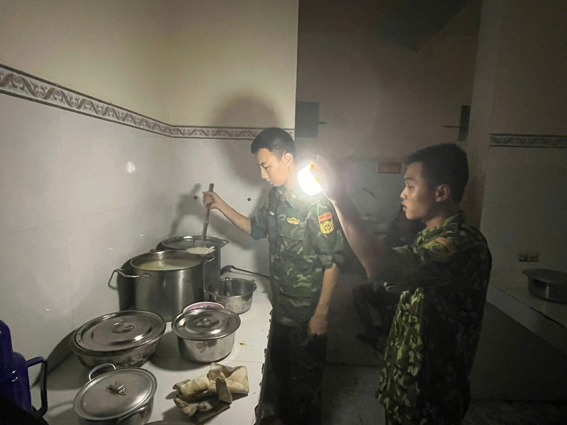 Các chiến sĩ thuộc Đồn Biên phòng Nhơn Châu dùng đèn pin nấu cháo cho người dân trong lúc mất điện.
