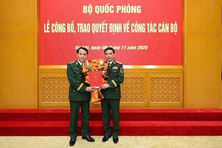 Thừa ủy quyền của Chủ tịch nước, Thủ tướng Chính phủ, Đại tướng Phan Văn Giang, Bộ trưởng Bộ Quốc phòng, trao quyết định và tặng hoa chúc mừng Trung tướng Vũ Trung Kiên (bên trái).