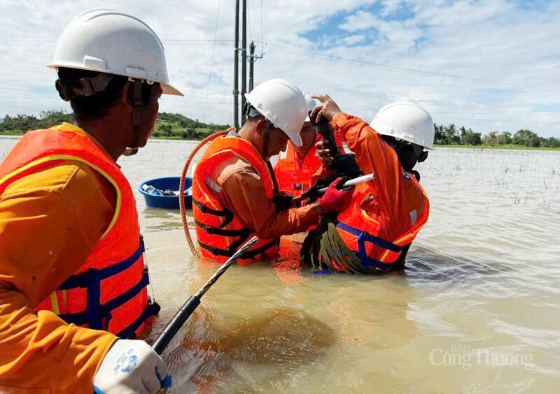 Cán bộ ngành điện nối lại đường dây điện giữa bối cảnh nước ngập nửa người. Ảnh: Hồng Hoa