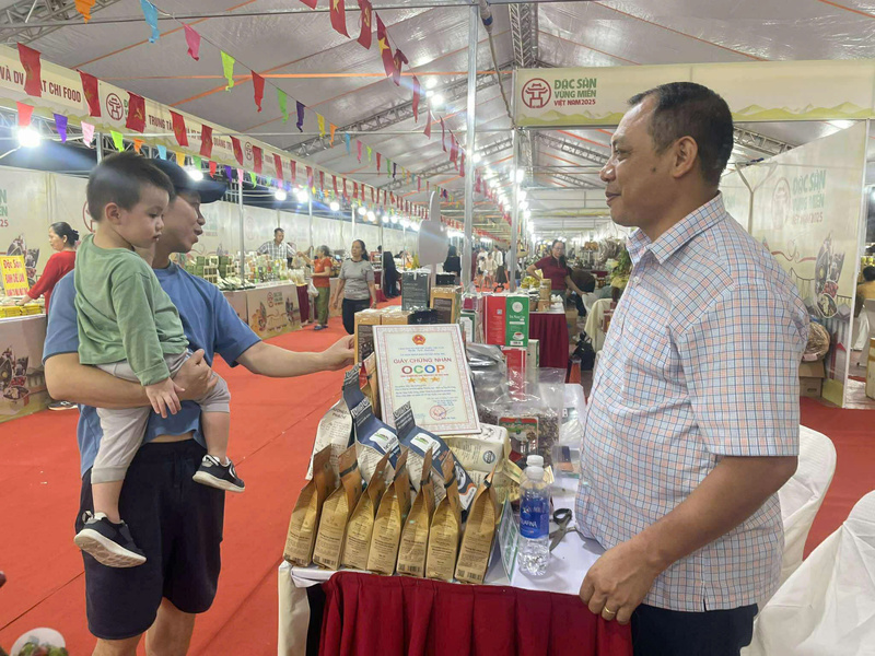 Chủ gian hàng đặc sản Lâm Đồng giới thiệu sản phẩm tới khách hàng.