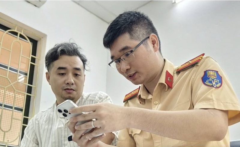 Cán bộ Cảnh sát giao thông hướng dẫn người dân thực hiện “Làm sạch dữ liệu” trên ứng dụng VNeTraffic. Ảnh: Cục Cảnh sát giao thông
