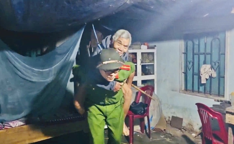 Chiến sĩ công an cơ sở đưa người già di chuyển tới nơi an toàn.