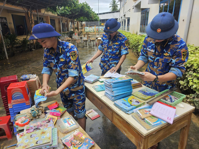 Cảnh sát biển vệ sinh sách, vở và dụng cụ học tập của học sinh Trường Tiểu học Thị trấn 1 Diên Khánh bị ngập trong nước lũ. Ảnh: Xuân Ngọc.