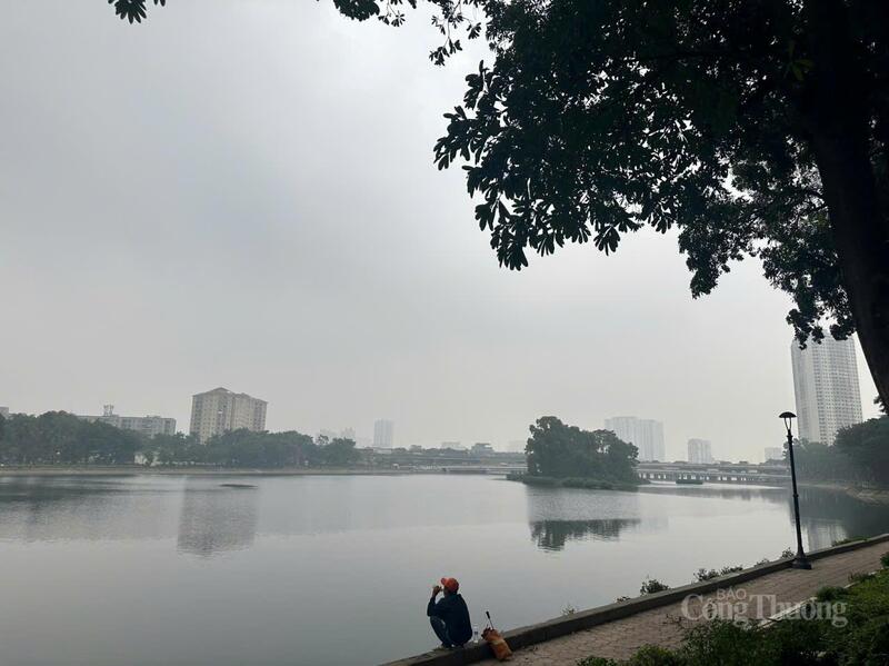 Người dân ngồi bên hồ Linh Đàm trong buổi sáng mù sương, bầu trời xám xịt do ô nhiễm không khí sáng 3/12.