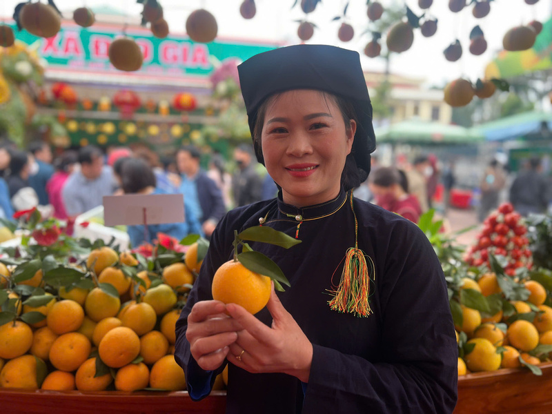 Bà Ninh Thị Triệu, chuyên viên Văn phòng HĐND-UBND xã Kiên Lao giới thiệu sản phẩm cam lòng vàng tại hội chợ. Ảnh: Thanh Thảo