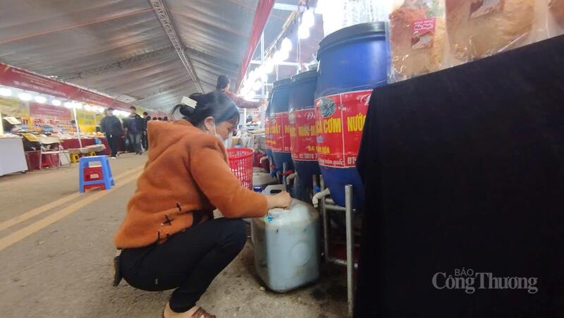 Chủ hàng sang chiết nước mắm đưa vào can bán cho khách hàng. Ảnh: Văn Thi