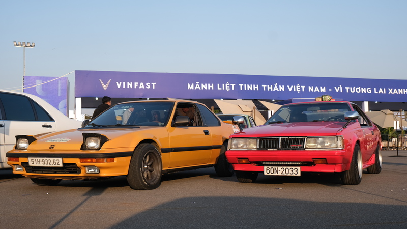 Hai mẫu xe thể thao cổ của Honda và Toyota xuất hiện tại khu Motorsport Zone, đại diện cho hai trường phái thiết kế và kỹ thuật Nhật Bản thập niên 1980-1990. Chiếc Honda với kiểu dáng nhỏ gọn, đèn pha bật lên đặc trưng đặt cạnh mẫu Toyota coupe dáng dài, gầm thấp, tạo nên điểm nhấn hoài niệm giữa không gian trình diễn xe hiện đại của Vietnam Mobility Show 2025.