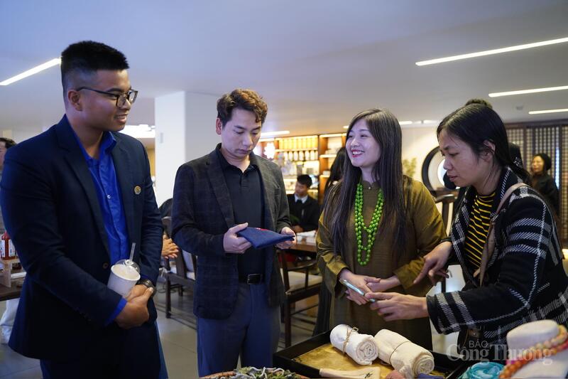 Chị Lương Thanh Hạnh, Giám đốc Hợp tác xã Lụa đũi Nam Cao (tỉnh Hưng Yên) (thứ 2 từ phải sang) đang trao đổi với khách hàng về sản phẩm của HTX. Ảnh: N.H