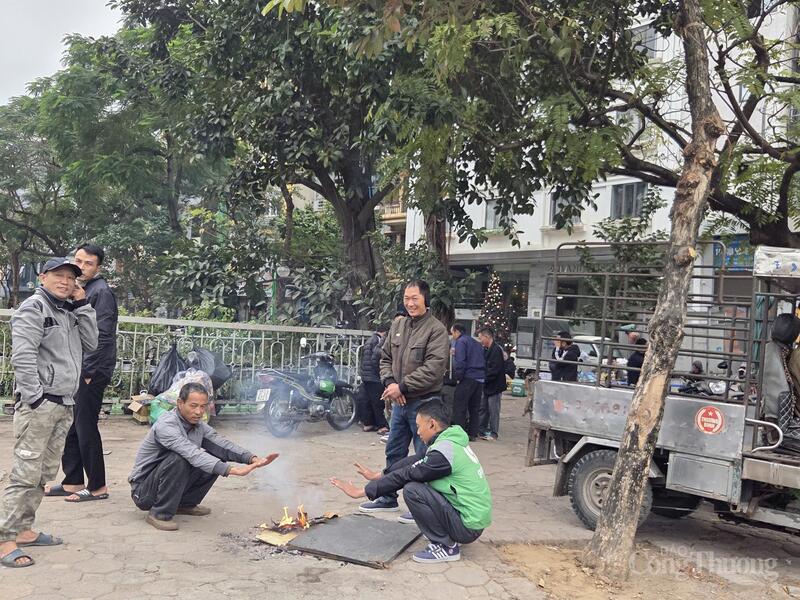 Những người lao đông ở khu vực chợ Bưởi đốt lửa sưởi ấm chiều muộn ngày 2/1/2026 trong lúc nghỉ ngơi.