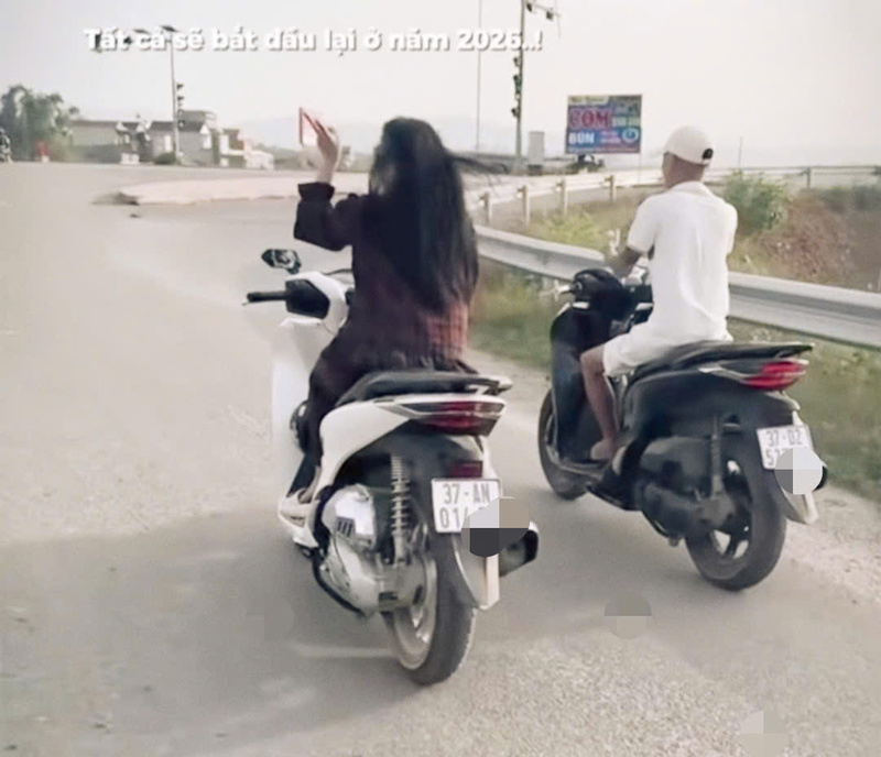 Hình ảnh cô gái điều khiển xe máy bằng một tay, đi cạnh nam thanh niên khác, cả hai đều không đội mũ bảo hiểm. Ảnh chụp lại từ clip.