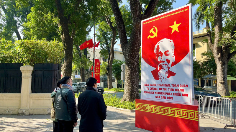 Người dân dừng chân theo dõi cụm pano tuyên truyền trên tuyến phố trung tâm Thủ đô, thể hiện sự quan tâm và đồng thuận xã hội trong không khí chào mừng Đại hội Đảng XIV.