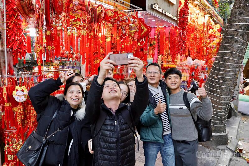 Sự phong phú về mẫu mã giúp phố Hàng Mã trở thành không gian chụp ảnh sôi động được nhiều người dân và du khách lựa chọn là điểm "check - in" khi đặt chân tới Hà Nội.Anh Nguyễn Tiến Dũng (30 tuổi, Thái Nguyên) và chị Vũ Kim Xuyến (26 tuổi, Ninh Bình) cùng dạo phố, chụp ảnh và tận hưởng không khí Xuân sớm. Gắn bó nghề buôn bán trên phố Hàng Mã nhiều năm, chị Đoàn Thanh Thư (áo đỏ) cho biết, thị trường Tết năm nay khởi động sớm nhưng diễn ra chậm rãi hơn thường lệ. Chị chia sẻ: “Không khí Tết đến sớm nhưng sức mua trải đều, không dồn dập như mọi năm do thời gian chuẩn bị Tết kéo dài hơn những năm trước". Chị Phạm Phương Nhung, 23 tuổi (Hải Phòng) cho biết, dịp Tết năm nay, gia đình chị kinh doanh đồ trang trí nên chị trực tiếp lên phố Hàng Mã nhập hàng về bán. Theo chị Nhung, giá năm nay ở mức hợp lý, dễ nhập buôn hơn so với năm trước. Chị nhận định: “Các loại mành, câu đối, khánh chúc mừng năm mới hay tượng thần tài vẫn được nhiều người quan tâm, năm nay khả năng vẫn bán tốt”.Cùng với đồ trang trí, các loại hộp đựng quà Tết cũng phong phú về mẫu mã, được bán với mức giá từ 70.000 đến 150.000 đồng.Ảnh: Phương Hà