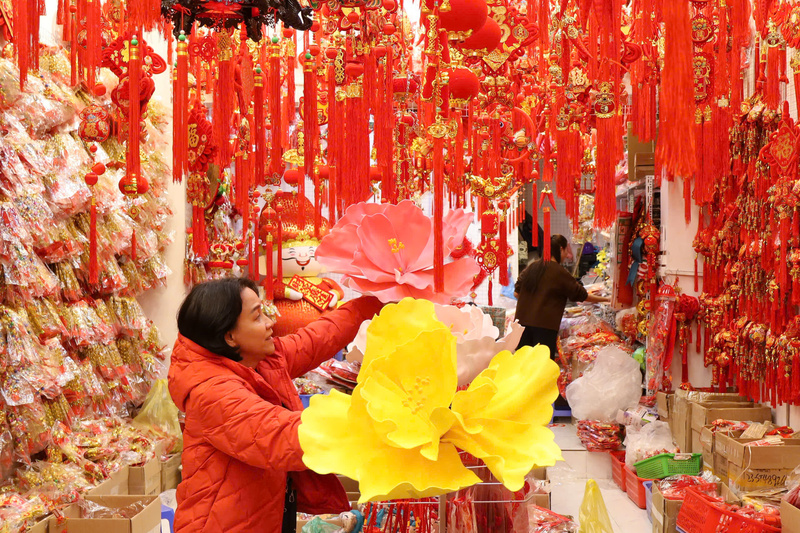 Gắn bó nghề buôn bán trên phố Hàng Mã nhiều năm, chị Đoàn Thanh Thư (áo đỏ) cho biết, thị trường Tết năm nay khởi động sớm nhưng diễn ra chậm rãi hơn thường lệ. Chị chia sẻ: “Không khí Tết đến sớm nhưng sức mua trải đều, không dồn dập như mọi năm do thời gian chuẩn bị Tết kéo dài hơn những năm trước". Chị Phạm Phương Nhung, 23 tuổi (Hải Phòng) cho biết, dịp Tết năm nay, gia đình chị kinh doanh đồ trang trí nên chị trực tiếp lên phố Hàng Mã nhập hàng về bán. Theo chị Nhung, giá năm nay ở mức hợp lý, dễ nhập buôn hơn so với năm trước. Chị nhận định: “Các loại mành, câu đối, khánh chúc mừng năm mới hay tượng thần tài vẫn được nhiều người quan tâm, năm nay khả năng vẫn bán tốt”.Cùng với đồ trang trí, các loại hộp đựng quà Tết cũng phong phú về mẫu mã, được bán với mức giá từ 70.000 đến 150.000 đồng.Ảnh: Phương Hà