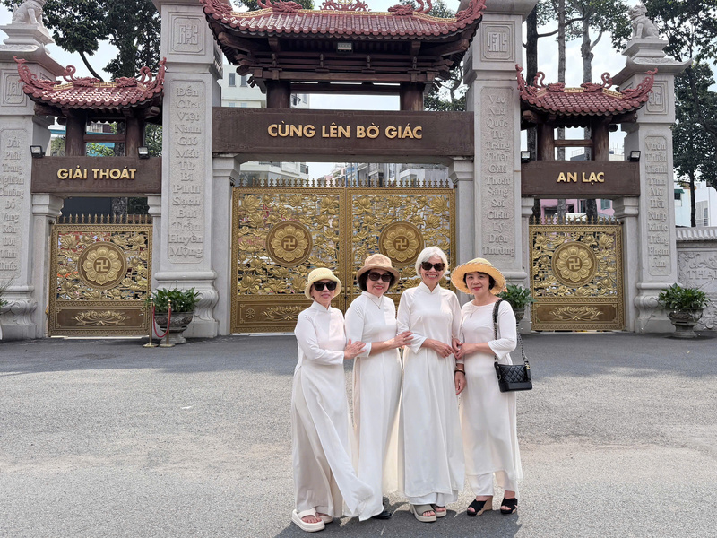 Nhóm du khách trung niên duyên dáng trong tà áo dài trắng tinh khôi, check-in trước cổng chùa. Ảnh: Minh Anh