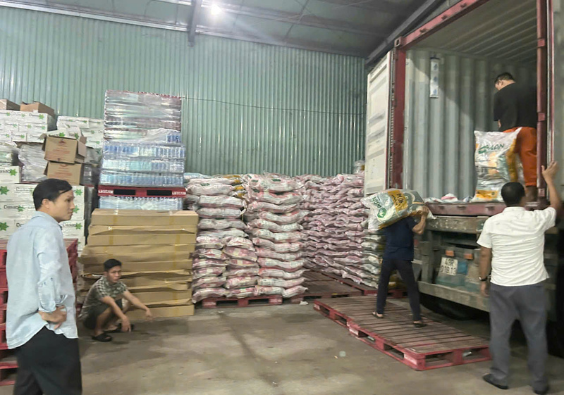 Các doanh nghiệp huy động thành viên trong gia đình để đưa hàng hoá lên xe. Điện cúp, nhân lực mỏng, công việc bốc hàng hoá cứu trợ khẩn cấp cho người dân vùng lũ chủ yếu bằng sức người. Ảnh: Nguyễn Tuấn