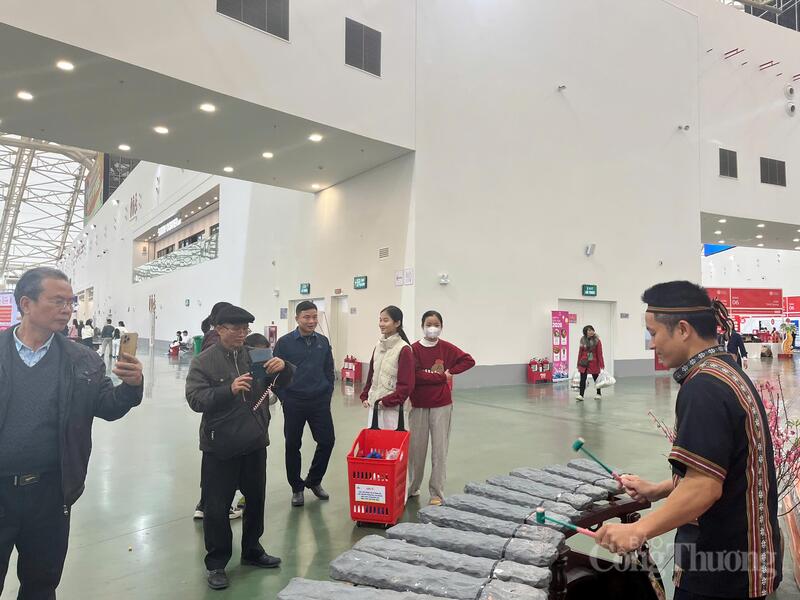 Đông đảo khách hàng tham quan dừng chân lắng nghe tiếng đàn của nghệ nhân.