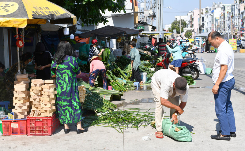 Nếu như vài ngày trước, lượng khách còn thưa thớt thì càng sát Tết, không khí mua bán càng trở nên nhộn nhịp. Nhiều gia đình, trường học và các đơn vị tổ chức hoạt động trải nghiệm truyền thống đã đến mua lá dong với số lượng lớn để gói bánh chưng, tạo khung cảnh tất bật đặc trưng của những ngày cận Tết. Ảnh: Thanh Minh