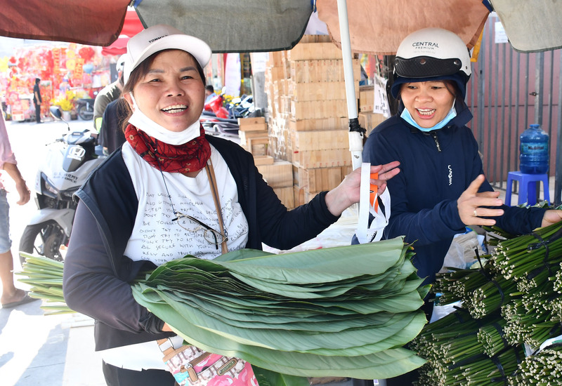 Tiểu thương Thu Đông - người đã gắn bó với nghề bán lá dong hơn 30 năm cho biết: Năm nay nguồn cung dồi dào hơn, lá đẹp, phong phú, giá bán cũng thấp hơn năm ngoái. Ba ngày trước còn vắng khách, nhưng hôm nay sức mua đã tăng rõ rệt, buổi sáng bán gấp đôi so với hôm qua. Ảnh: Thanh Minh