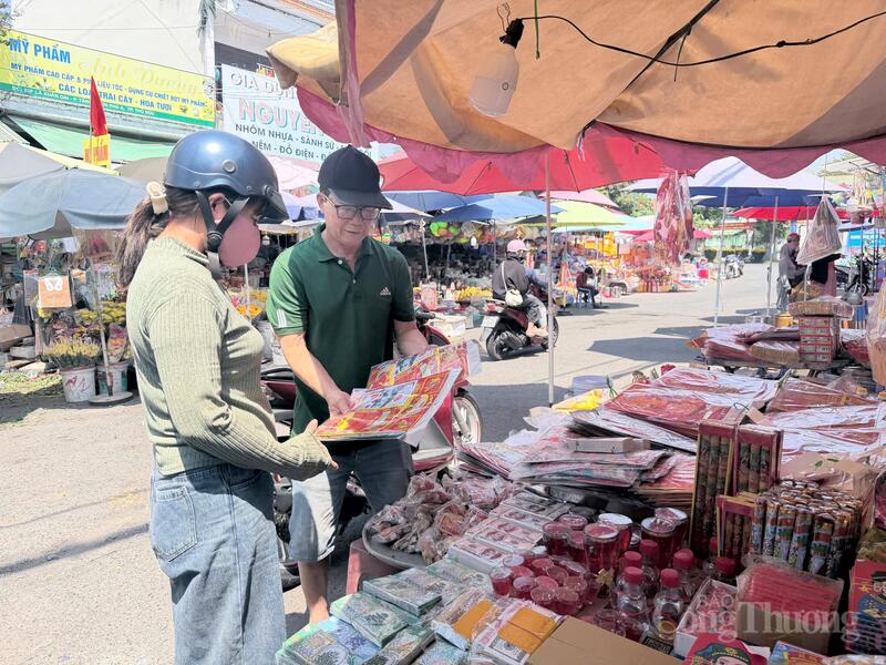 Ông Ba Chánh, một tiểu thương lâu năm tại chợ Thủ Đức, đang giới thiệu các mẫu đồ mã cúng ông Công ông Táo cho khách hàng. Ảnh: Minh Anh