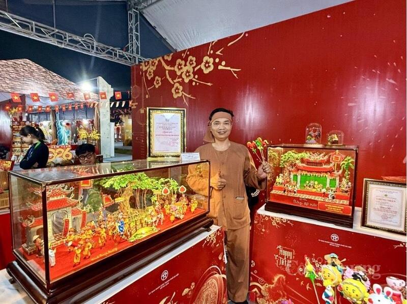 Nghệ nhân tò he Đặng Văn Sừ bên cạnh hai tác phẩm “Vinh quy bái tổ” và “Phường rối nước”. Ảnh: Diệu Anh.