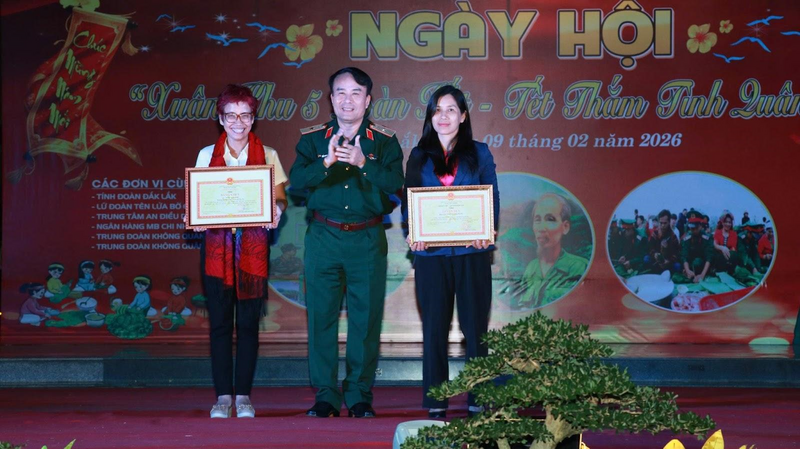 Đại diện Dự án “Một vòng tay ấm” - Nhà báo Trần Mai Anh (áo trắng) và Phóng viên Ái Linh, Phòng thời sự, Trung tâm truyền hình Việt Nam khu vực miền Trung Tây Nguyên nhận Bằng khen do Thiếu tướng Trần Minh Trọng- Ủy viên Ban Thường vụ Đảng uỷ - Phó Chính uỷ Quân khu 5 trao tặng