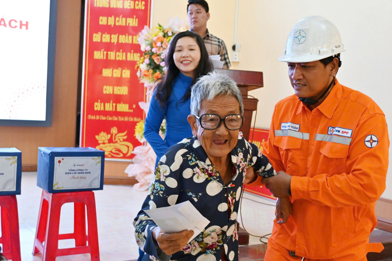 Nhân viên điện lực hỗ trợ những người cao tuổi đến nhận quà. Ảnh: PC An Giang