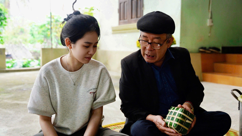 Người ông tỉ mỉ hướng dẫn cháu gái cách gói bánh chưng, truyền lại hương vị Tết và nếp nhà qua từng nếp lá. Ảnh: Diệu Linh