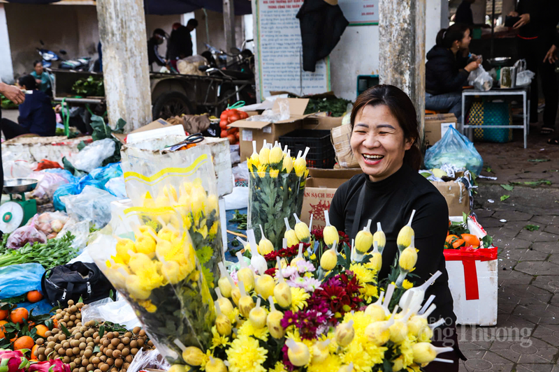 Những sạp hàng vốn giản dị ngày thường giờ đây rực rỡ sắc màu của hoa cúc, hoa vạn thọ, cùng những tập lá dong xanh ngắt.