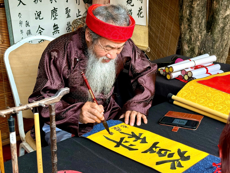 Các thầy đồ tỉ mỉ đề chữ, gửi tặng những vị khách nhỏ tuổi. Ảnh: Diệu Anh