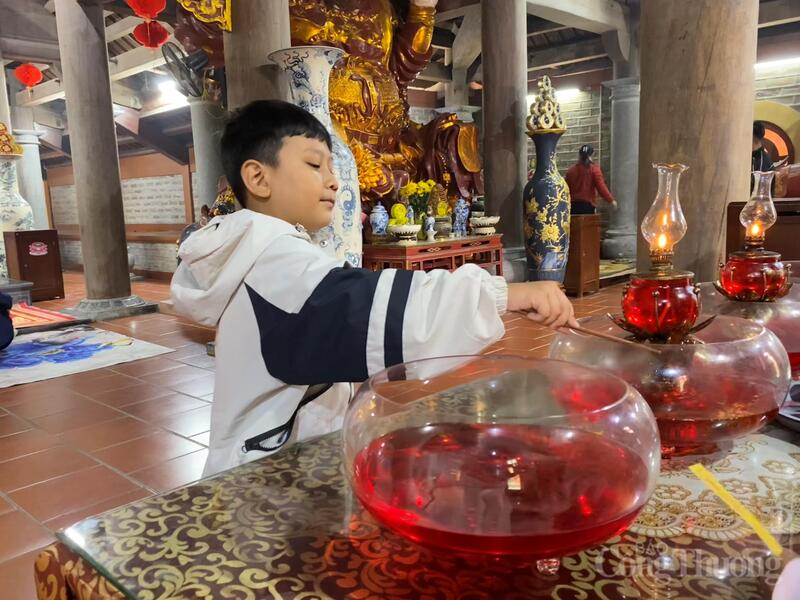 Trẻ nhỏ được người lớn hướng dẫn rót giọt dầu vào đèn và học cách gìn giữ nét đẹp tín ngưỡng truyền thống.