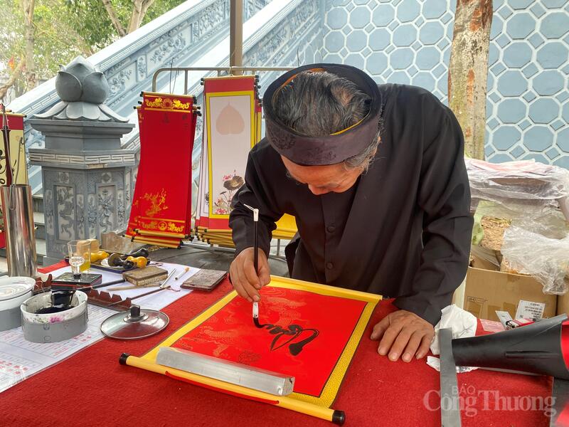 Bên hiên đền, hình ảnh ông đồ tỉ mỉ viết từng nét chữ thư pháp, gửi gắm lời chúc bình an, tài lộc trong ngày đầu năm mới góp phần làm đậm thêm sắc xuân truyền thống.