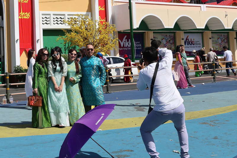 Không chỉ tự chụp bằng điện thoại, nhiều nhóm du khách còn thuê thợ ảnh riêng để ghi lại những khoảnh khắc chỉn chu nhất trong bộ áo dài truyền thống trước cửa chợ Bến Thành. Ảnh: Minh Anh