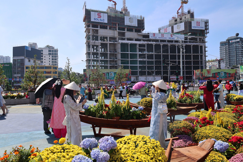 Người dân TP.Hồ Chí Minh xúng xính áo dài dạo phố và chụp ảnh lưu niệm tại không gian hoa xuân trước khu vực Chợ Bến Thành trong những ngày đầu năm mới 2026. Ảnh: Minh Anh.