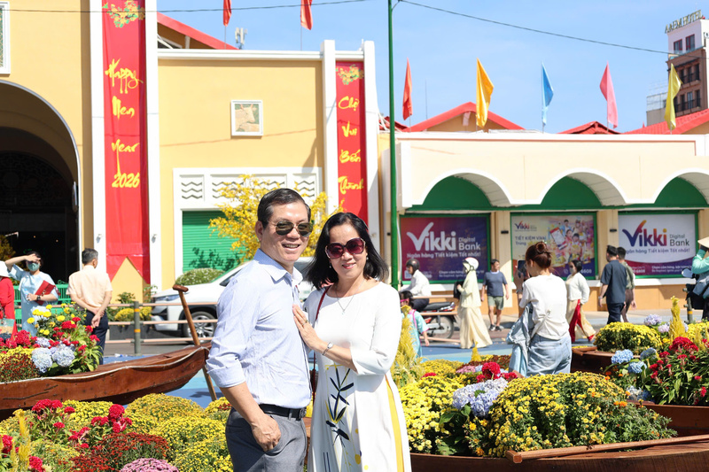 Du khách lưu giữ những khung hình hạnh phúc bên các tiểu cảnh hoa xuân trước ngôi chợ biểu tượng trăm năm. Ảnh: Minh Anh