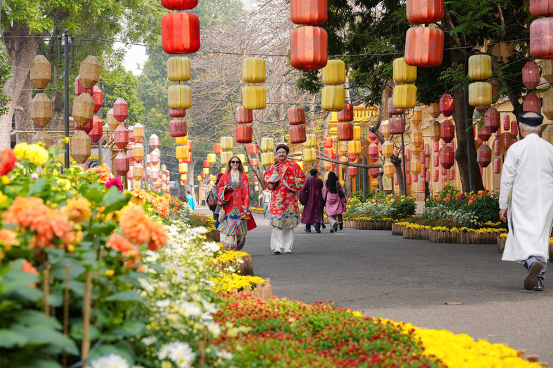 Du khách quốc tế thích thú trải nghiệm Tết Việt giữa sắc hoa rực rỡ và kiến trúc cổ kính của Hoàng thành. Ảnh: Tường Vy