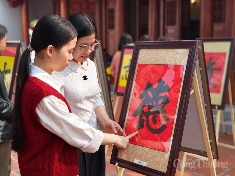 Các bạn trẻ tìm hiểu về chữ viết thư pháp.